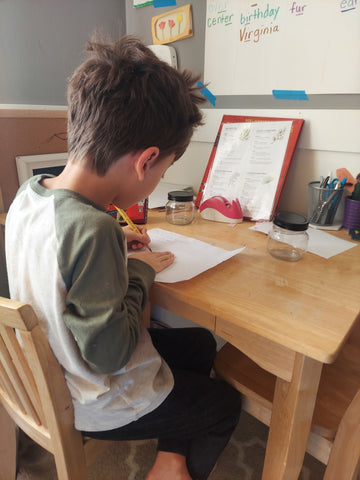 Student sitting at his desk writing words on a piece of paper.