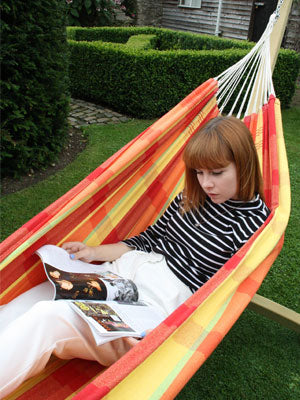 Woman lying on back in hammock reading magazine