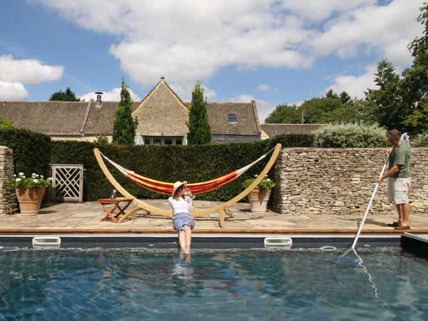 Woman with feet in pool drinking gin