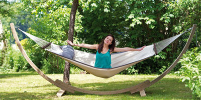 Woman sat on hammock supported by wooden hammock stand