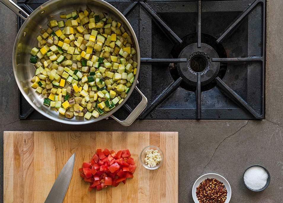 Hierro fundido vs. acero inoxidable: verduras cortadas en cubitos en una sartén de acero inoxidable