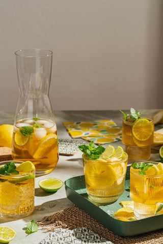 Lemon Mint Sparkler Iced Tea in tall straight pitcher with two glasses of tea on a tray in the foreground 