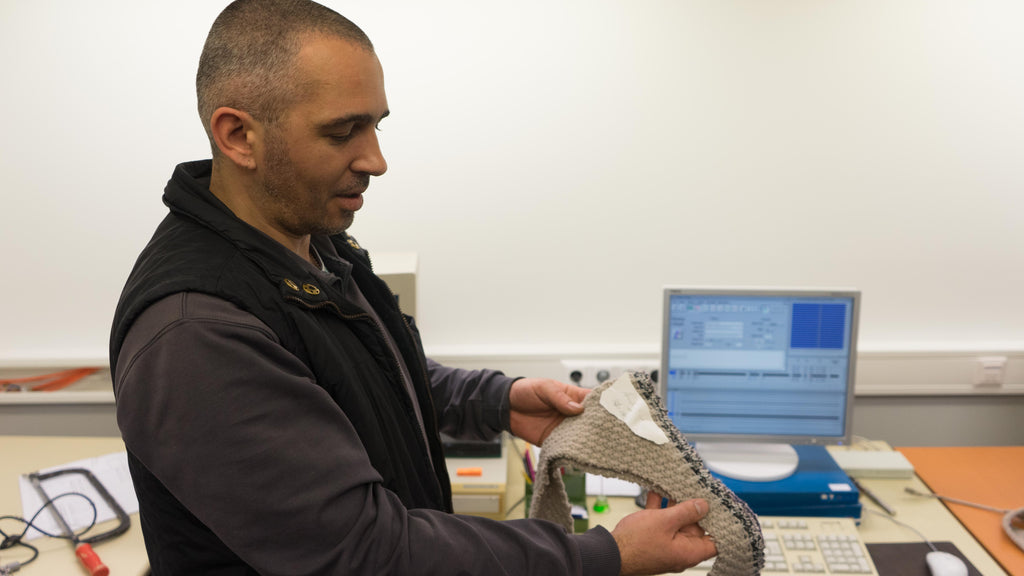 man showing how the computer programed sample turns out in real life after it is knitted