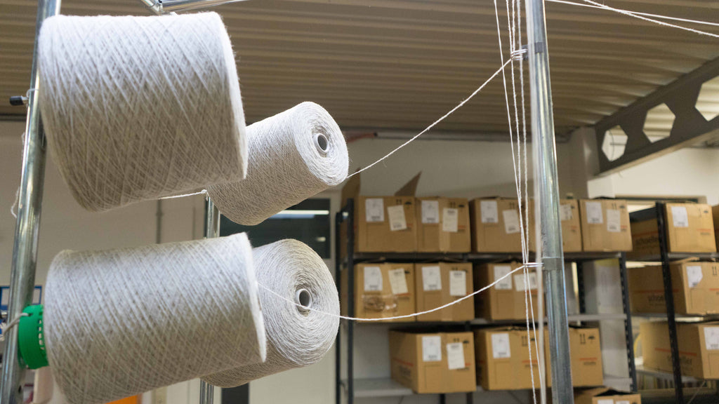 wool yarn on spools being drawn into knitting machine