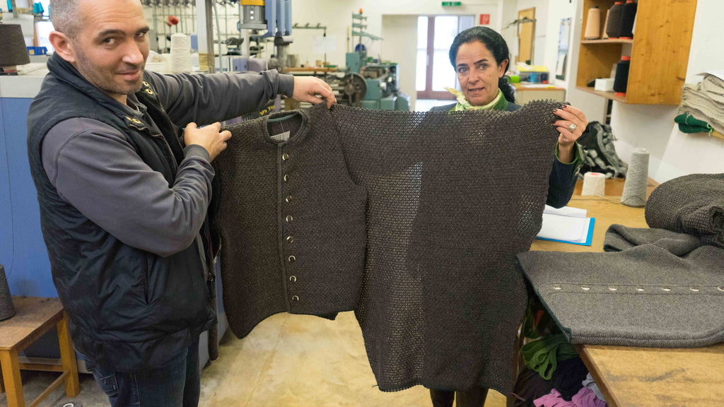 man and women holding up a finished shrunk wool jacket and a piece of the jacket before it was shrunk