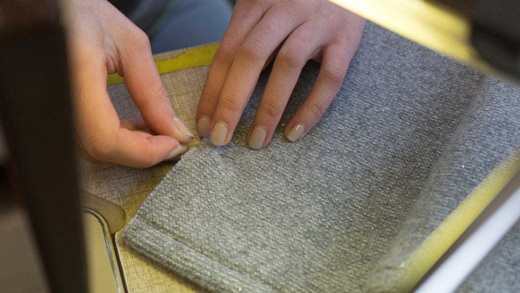 woman's hands sewing a wool jacket