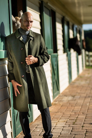 man wearing traditional austrian loden hunting coat in green at horse stable in Potomac Maryland