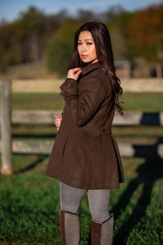 young woman wearing bark brown Robert W. Stolz loden wool coat in front of fence 