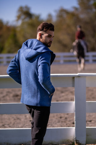 young man wearing blue boiled wool hoodie from Robert W. Stolz watching a horseback rider in Potomac Maryland