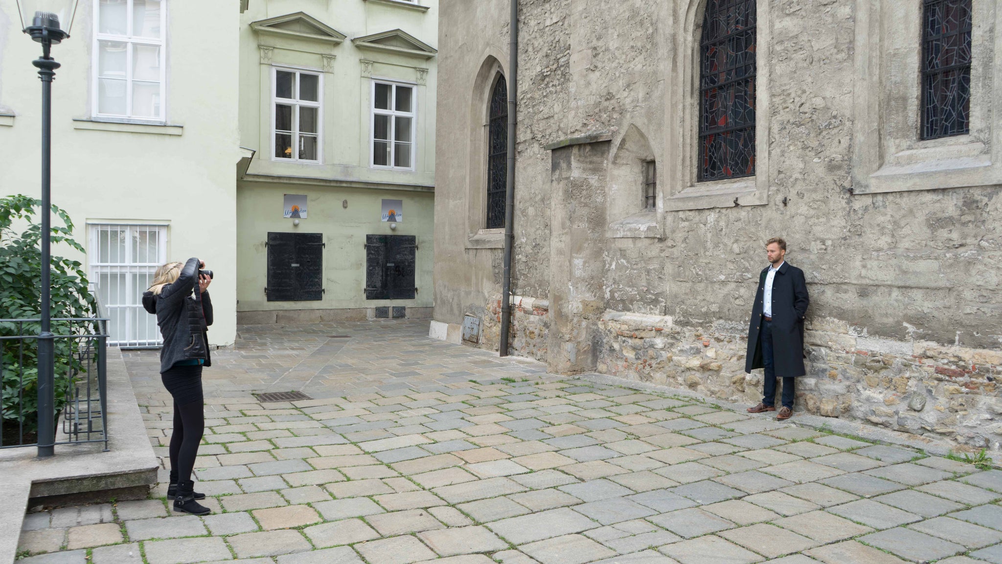 Photographer Astrid Schweyer on October 8, 2016 taking a picture of Yannick modeling the long overcoat for Robert W. Stolz in front of the St. Rupert Church in Vienna, Austria