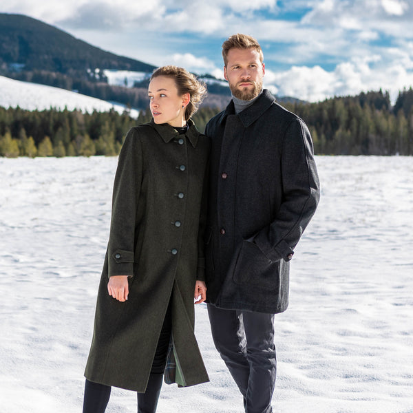 young man and women in a snowy field wearing loden coats