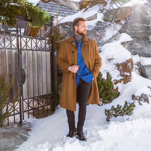 young man wearing camel colore long loden coat with blue tyrolean jacket underneath