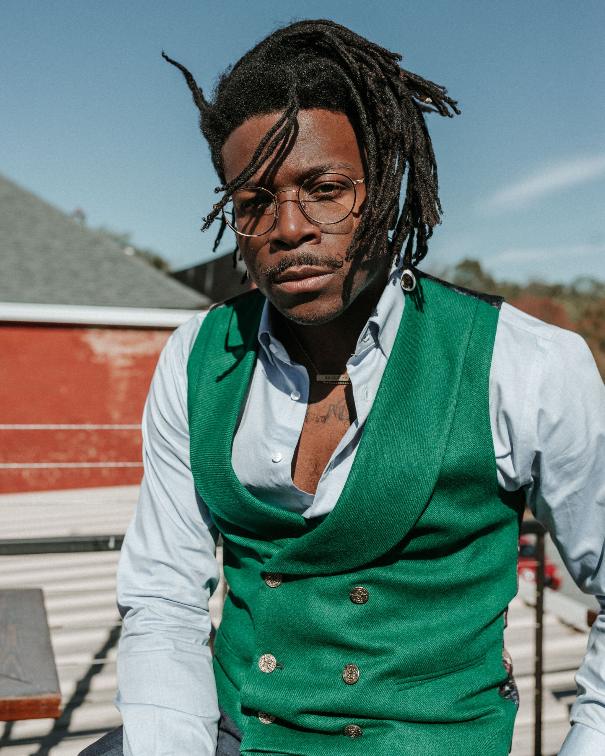 man wearing a green wool front double breasted shawl collar men's vest with gold tone buttons 