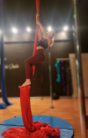 Girl climbing up a Red Aerial Silks