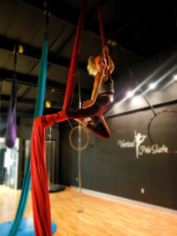 Girl doing a Single Knee Hang in our Red Aerial Silks