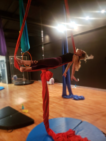 Girl doing a Coffin pose in our Red Aerial Silks