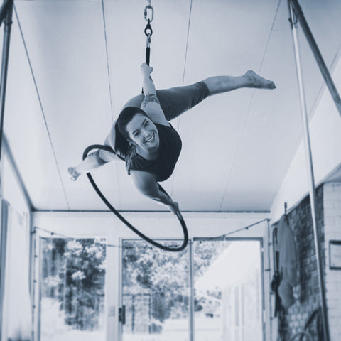 Black and white picture of a girl happily swinging on her Aerial hoop or Lyra