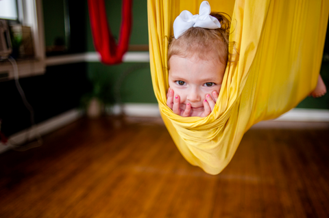 Little girl laying on a yellow hammock