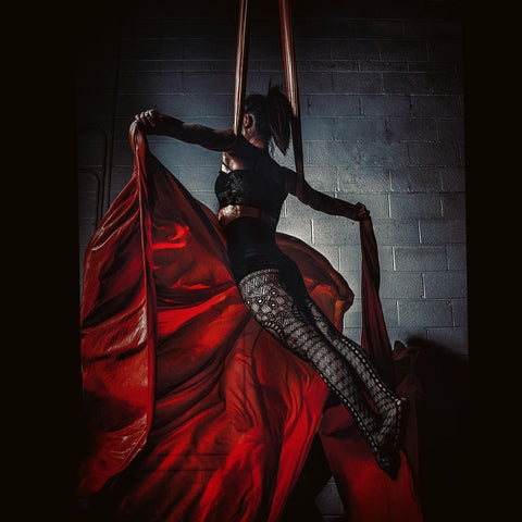 Girl holding a pose on a Red Aerial Silks