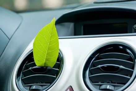 A green leaf in a car vent depicting fresh breathing air