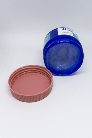 A jar of vapor rub sits on its side with a cap off