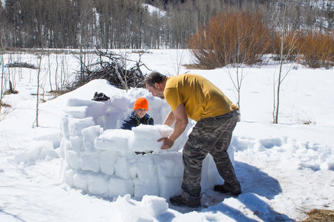 man building snow fort with son