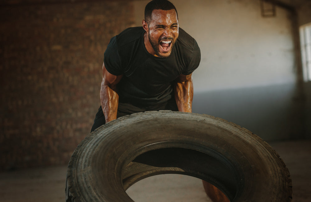 man performing intense workout with tyres