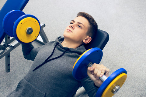 teenaged boy doing dumbbell presses