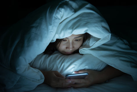 woman in bed with phone has insomnia