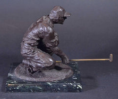 picture of a bronze golf sculpture of a male eyeing the green