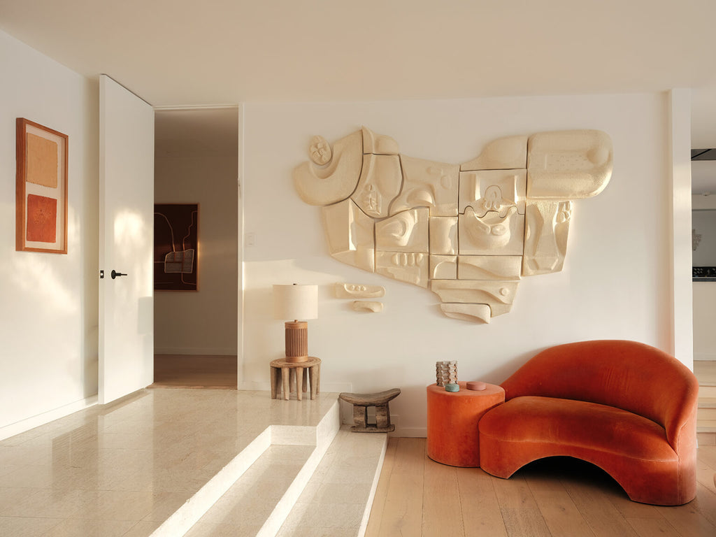 A light, minimal room with abstract wall art and corner sofa feature