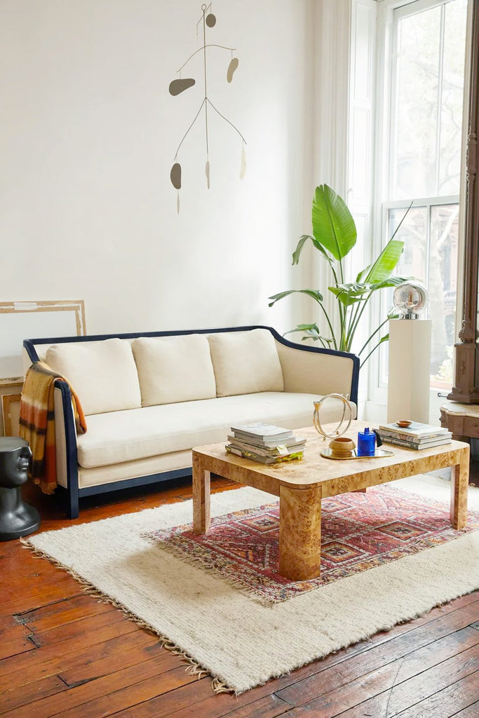 A lounge with wooden floor, ornate fireplace, rug, and armchairs