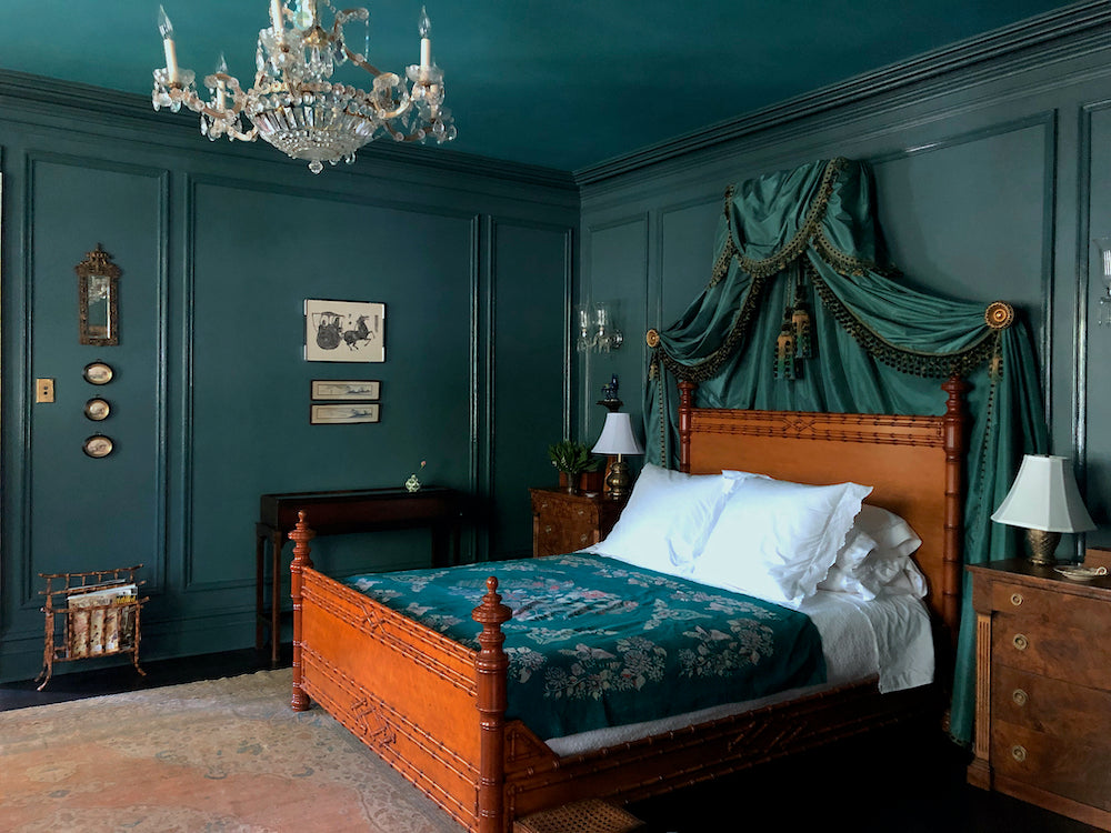 A traditionally decorated bedroom with antique bed, chandelier, and furniture
