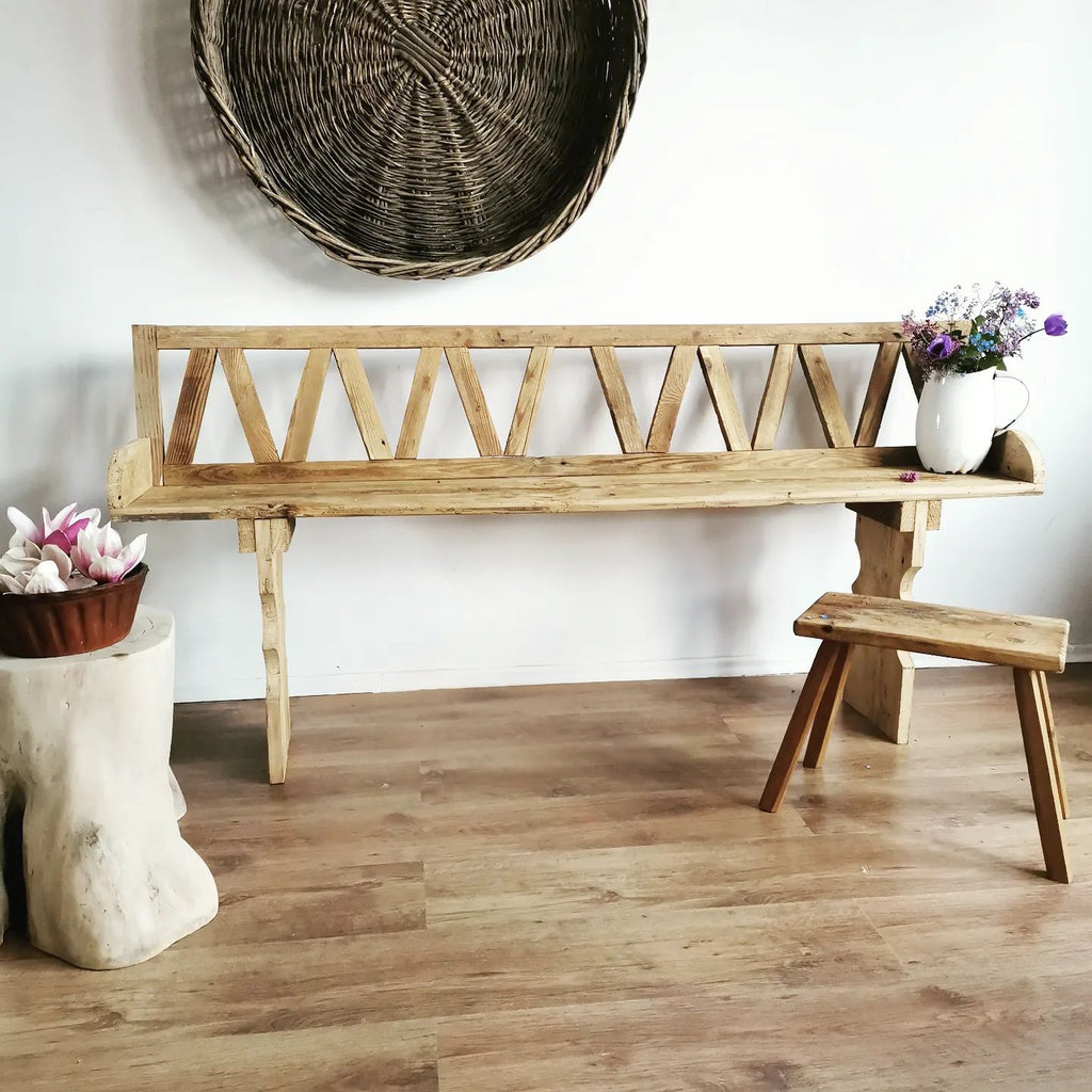 A minimal room with wooden floorboards, bench, and stool