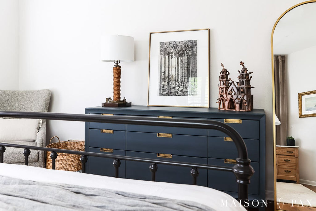 A bedroom decorated in the transitional style, with dresser, bed, and mirror