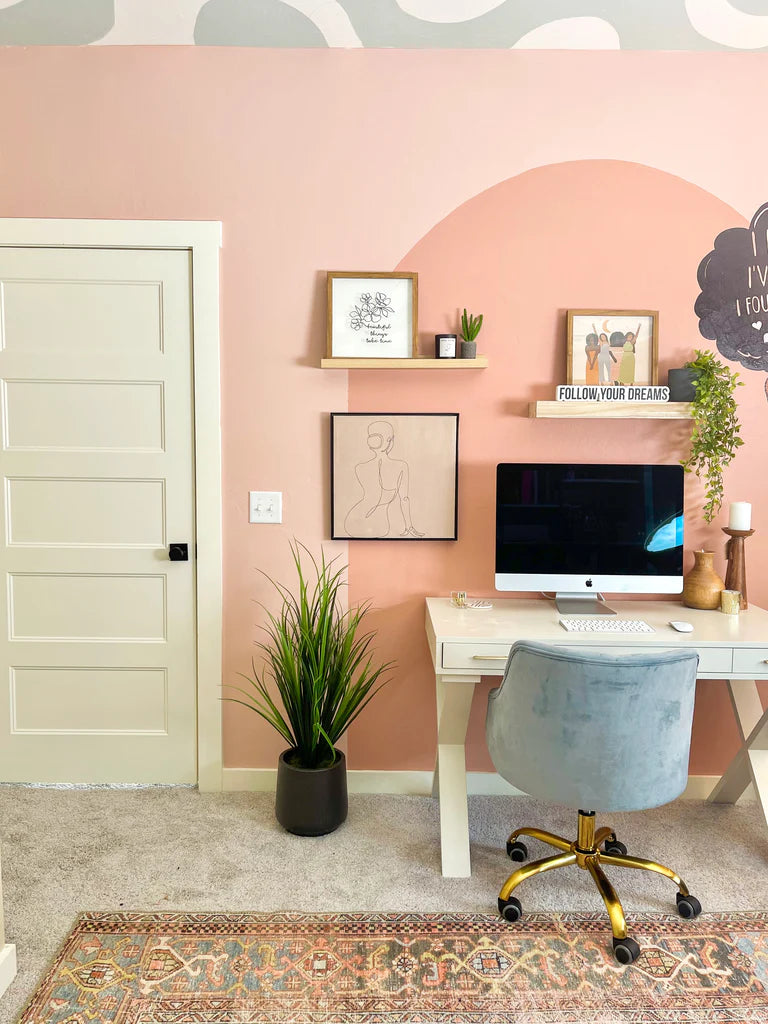 A home office space decorated with rug and pastel pink walls.