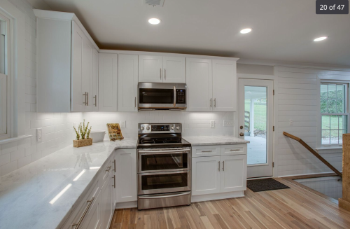 A spacious modern kitchen with white worktops and cupboards, and a wooden floor