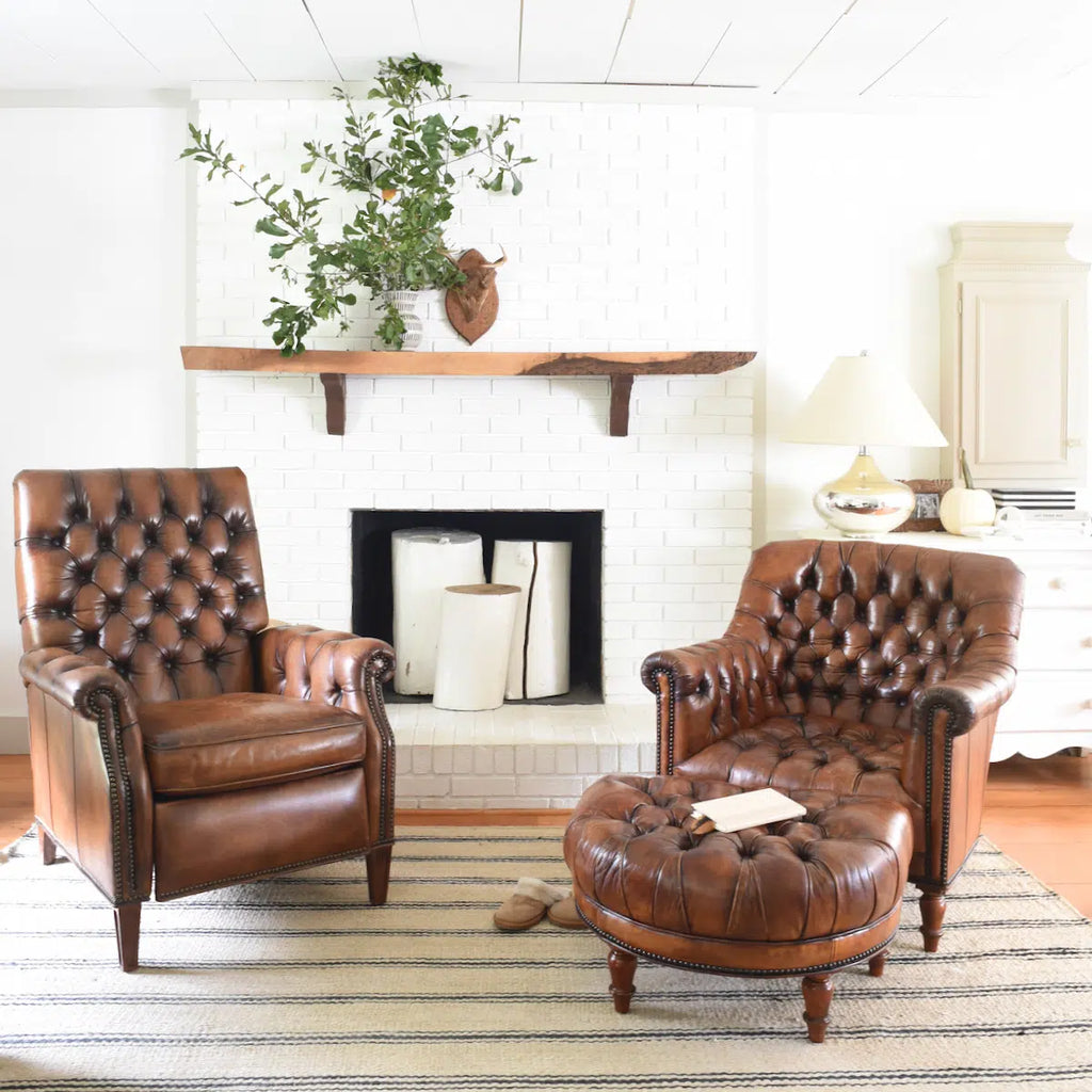 A brightly-lit interior with wooden floorboard, rug, and two traditional leather armchairs