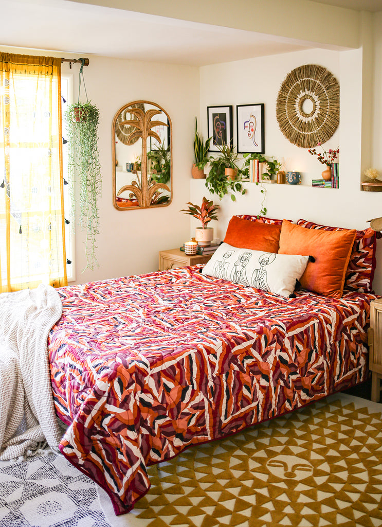 A colorfully-decorated bedroom with wall art, houseplants, and a mirror