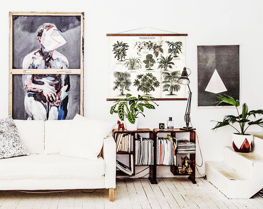 A wooden-floored room with sofa, shelving units, and wall art