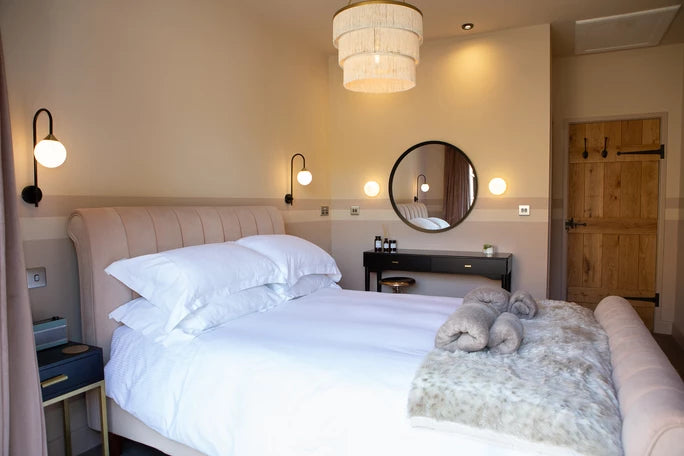 A bedroom with double bed, wall-mounted lamps, and wooden door