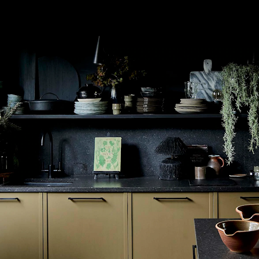 A kitchen with charcoal-colored worktops, shelves, and walls
