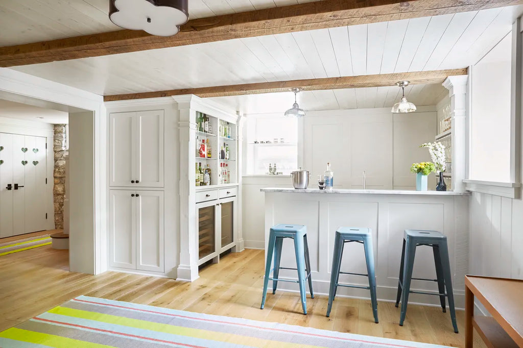 A spacious decorated basement with wooden floorboard and white painted wall panels