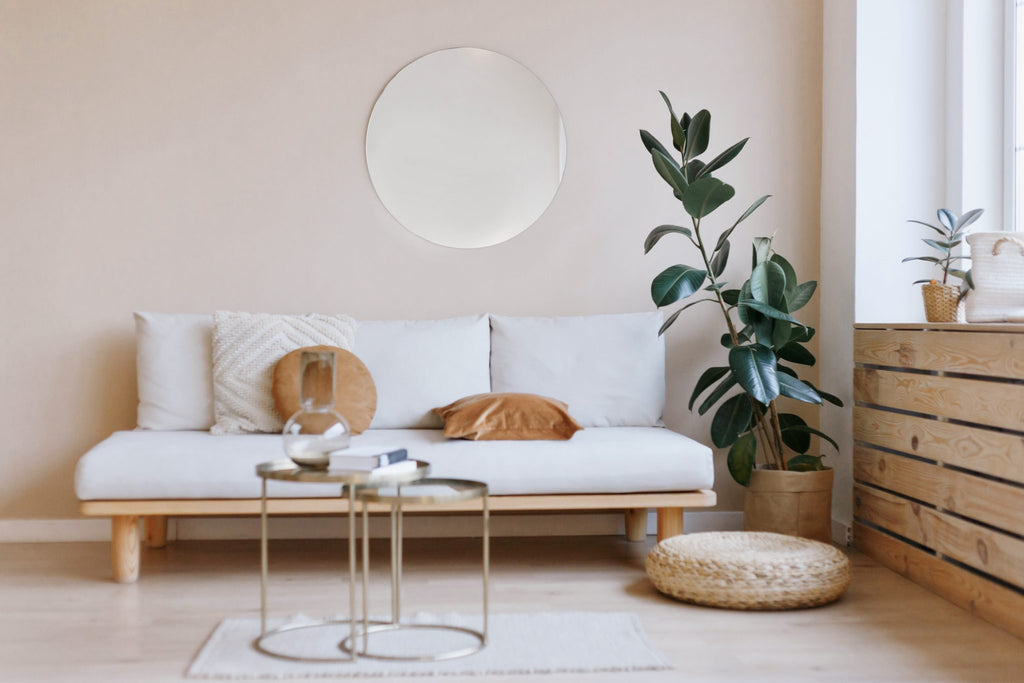 A minimally-decorated room with warm neutral tones, a sofa, coffee table, and houseplant