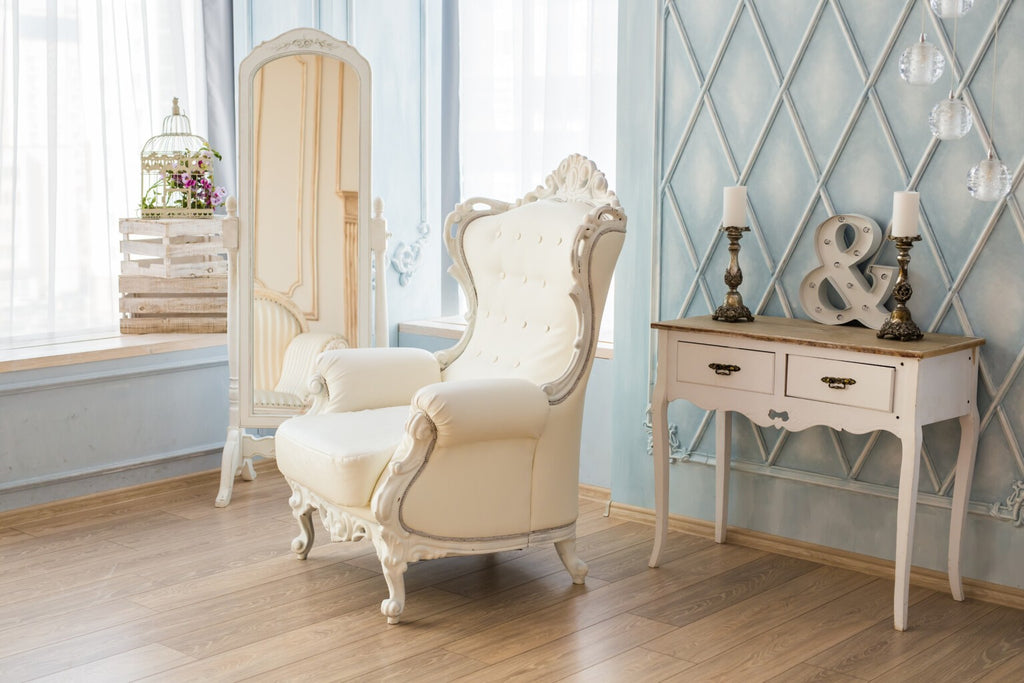 A traditional armchair next to a mirror and table, on a wooden floor