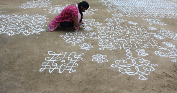 A woman drawing design on a mud floor
