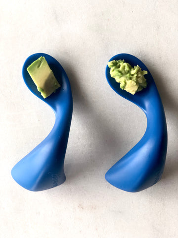 two blue curved spoons with mashed and diced avocado