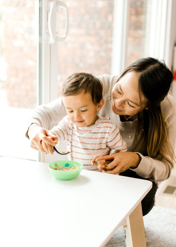 mom encouraging her son to use a spoon