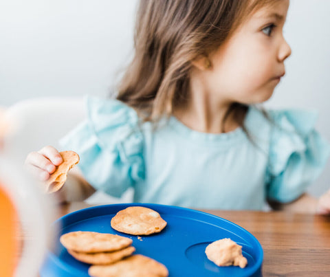 girl sitting at table eating pancakes for breakfast