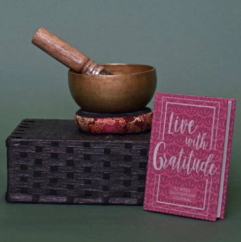 meditation bowl and pillow on box with pink gratitude journal sitting beside
